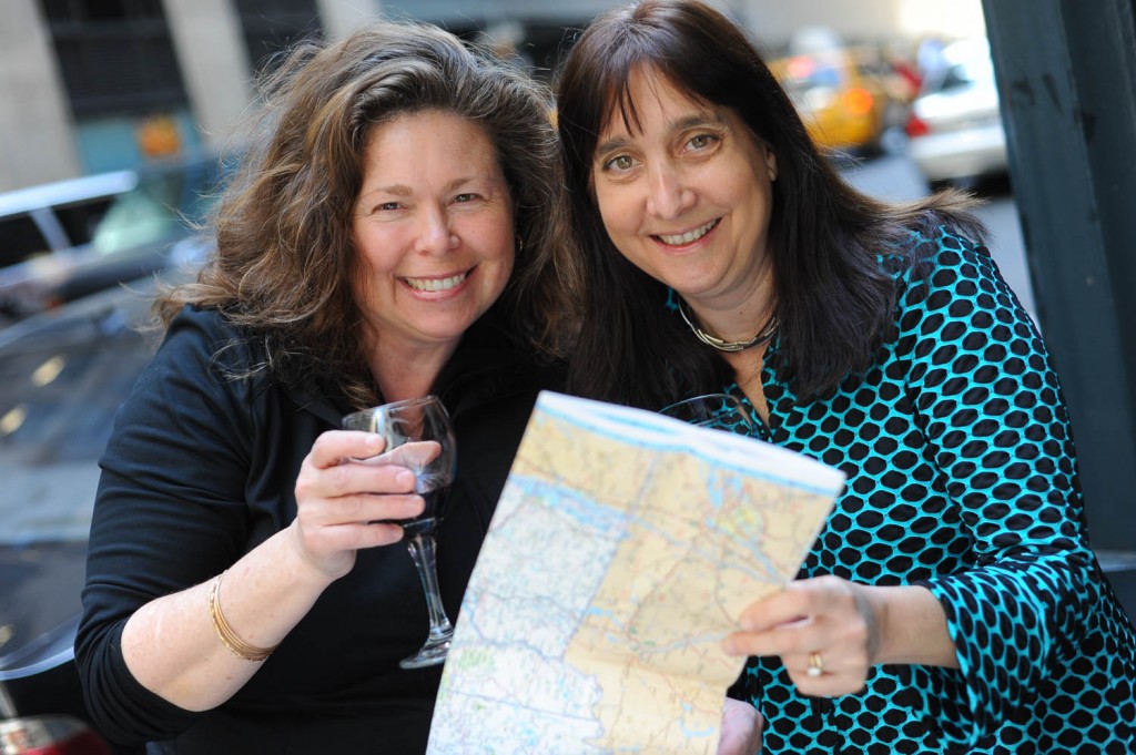 Getaway Mavens authors Sandra Foyt and Malerie Yolen-Cohn hold up a wine glass and road map.