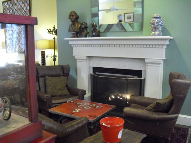 Fireplace – fire engine door coffee table – leather wingback chairs – lobby of hotel a former firehouse. | Cambridge MA