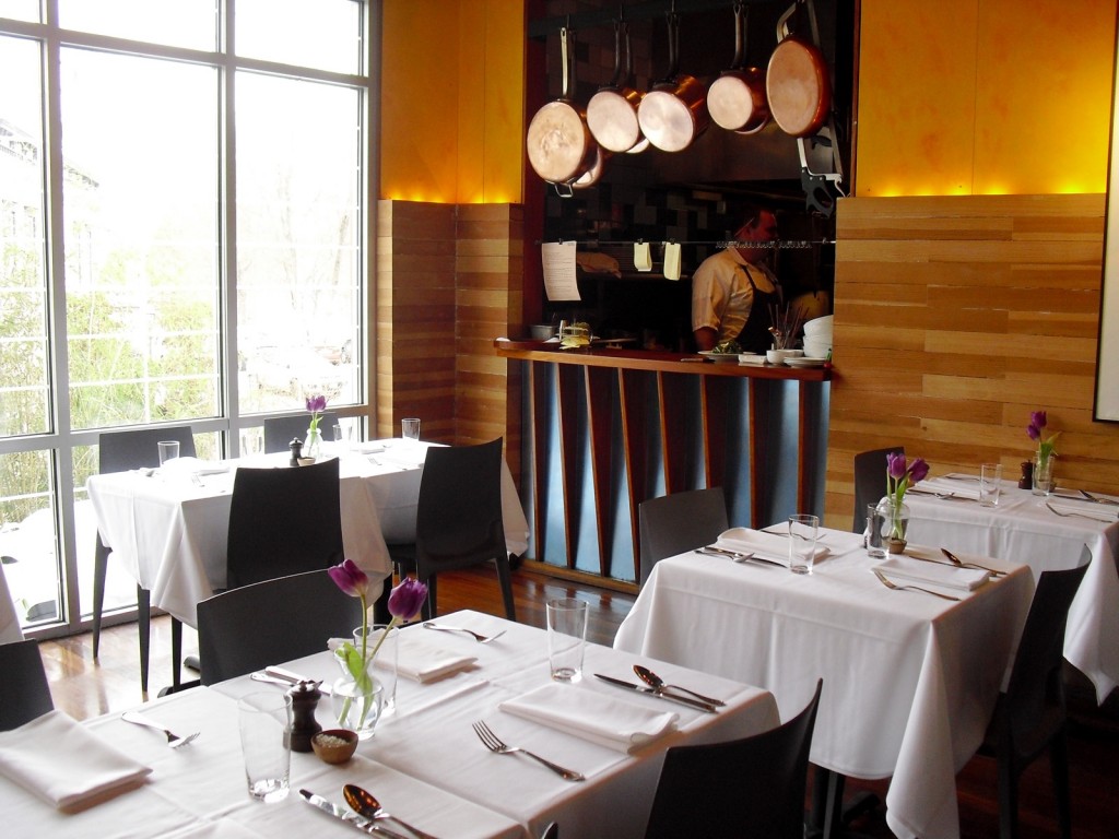 Dining room of modern farm to table restaurant - white linen tablecloth - open kitchen. - River Tavern - Chester CT