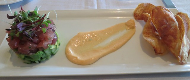 Beautifully plated raw tuna, avocado and hand-cut kettle chips with swoosh of sauce 