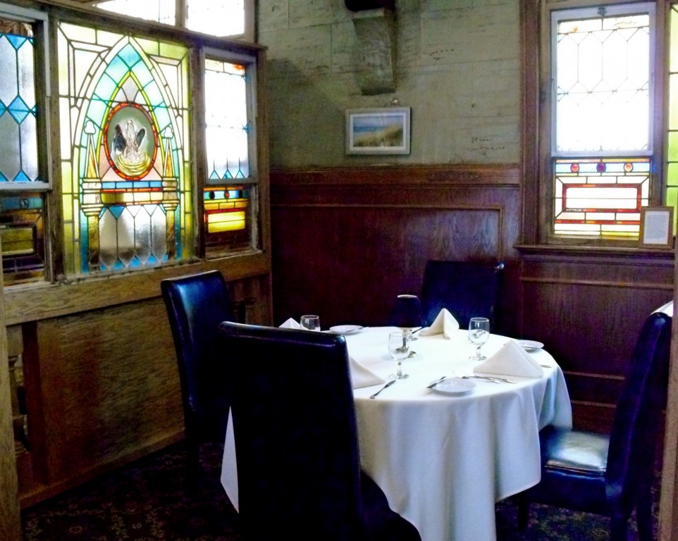 upscale dining linen table-set nook with Church-style stained glass. Belfry Inne Bistro, Sandwich MA
