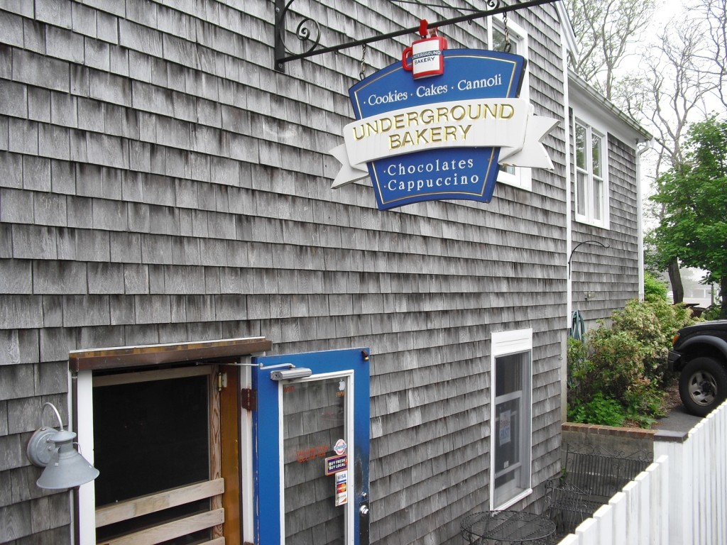 exterior shot of weathered grey clapboard building and bakery sign