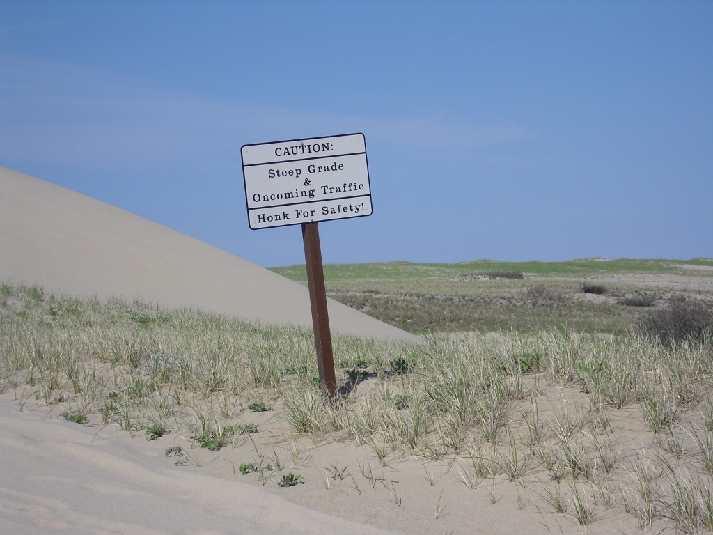 Caution sign warn of steep grade and oncoming traffic on sand dunes