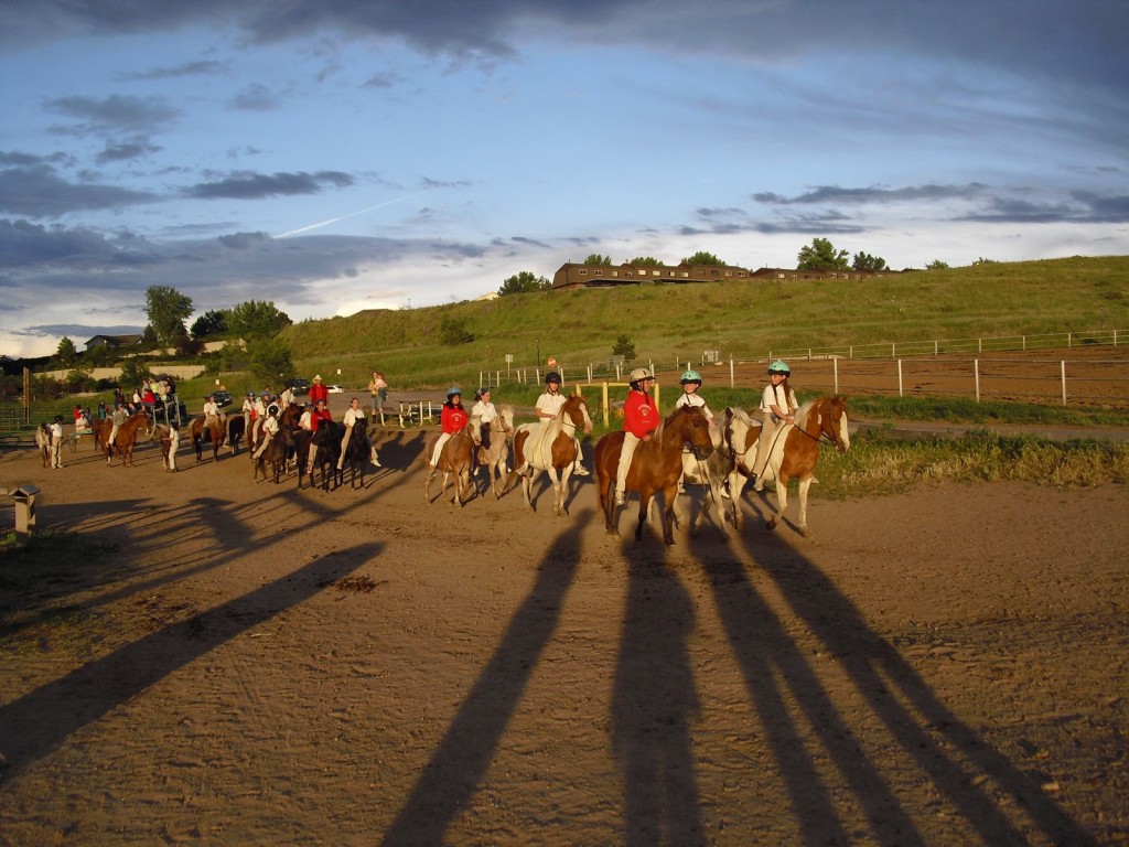 Young horse riders in setting sun at the foothill of the Rocky Mountains