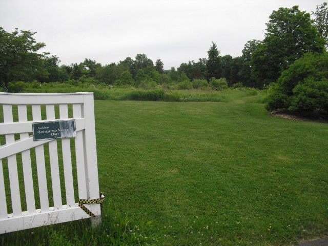 Picket fence opens onto pastoral green field at Greenwich CT Audubon Center