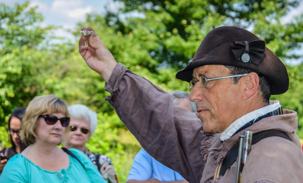 Docent, dressed in Continental Army uniform, at Valley Forge National Historical Park demonstrates how to shoot musket.