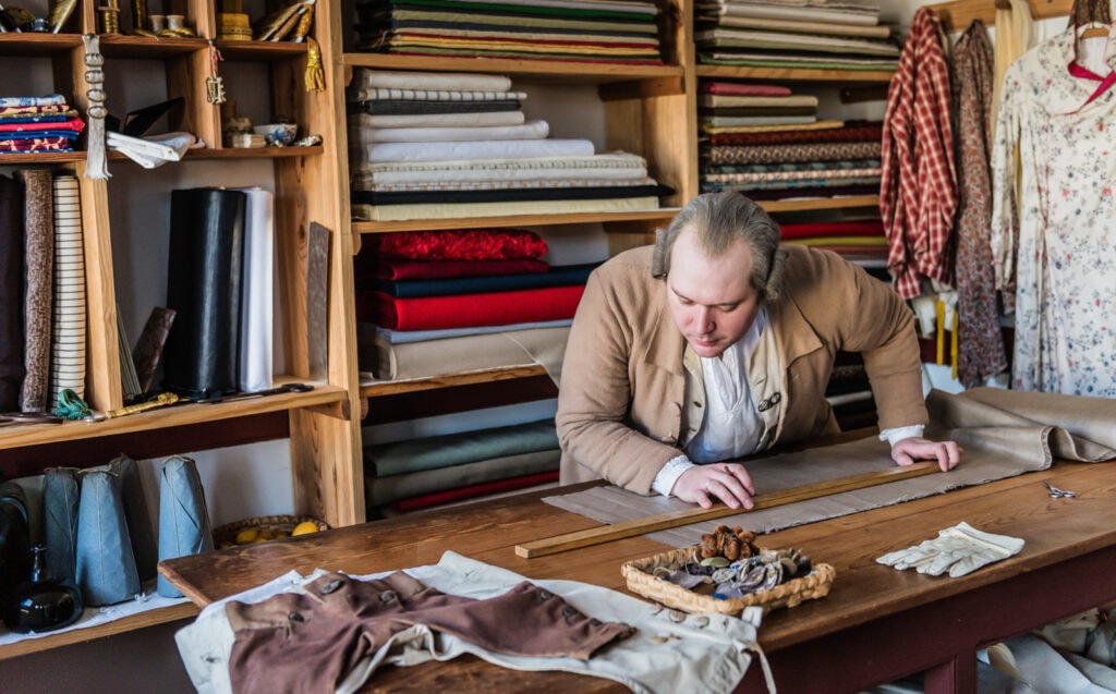 Tailor cuts cloth in Colonial Williamsburg Historical Site