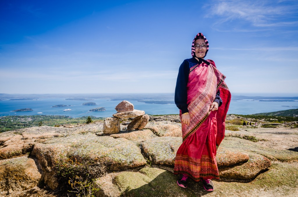 Indian matron wearing a pink sari stand next to a cairn atop Cadillac Mountain in Acadia National Park.