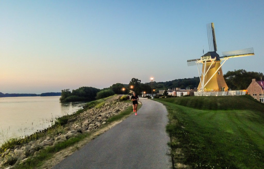 Woman running past Dutch Windmill on the Great River Trail along the Mississippi River.