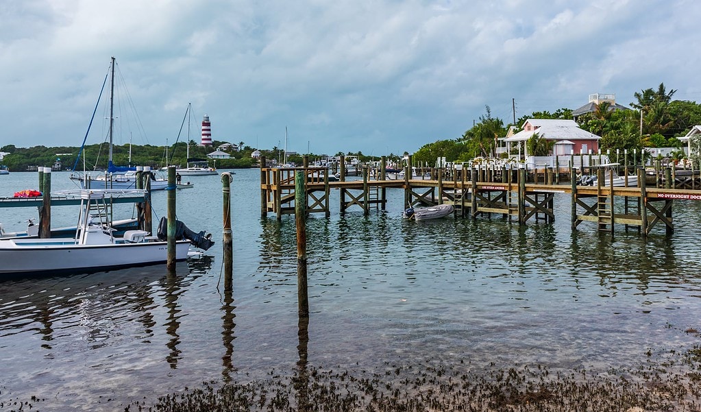 Pictures of Hope Town Bahamas shows harbor, dock, buildings, and lighthouse inn the background.