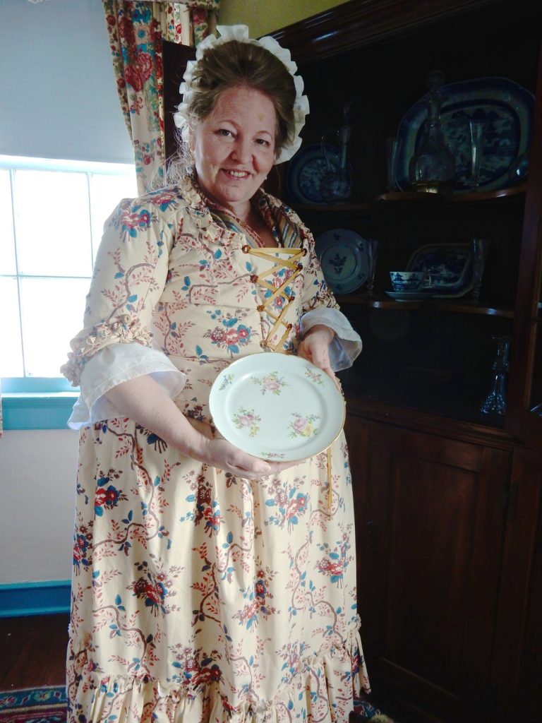 Docent Pat Sanftner holds up china plate at Schuyler Hamilton House in Morristown NJ