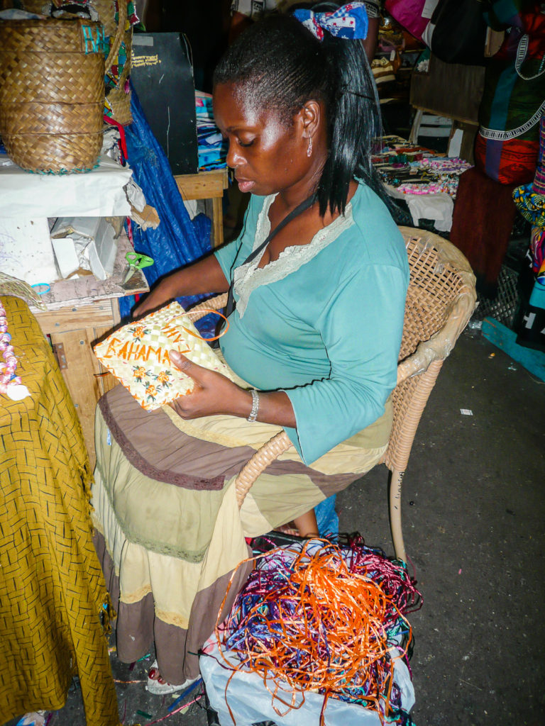Woman embroidering straw bag at The Straw Market in Nassau Bahamas.