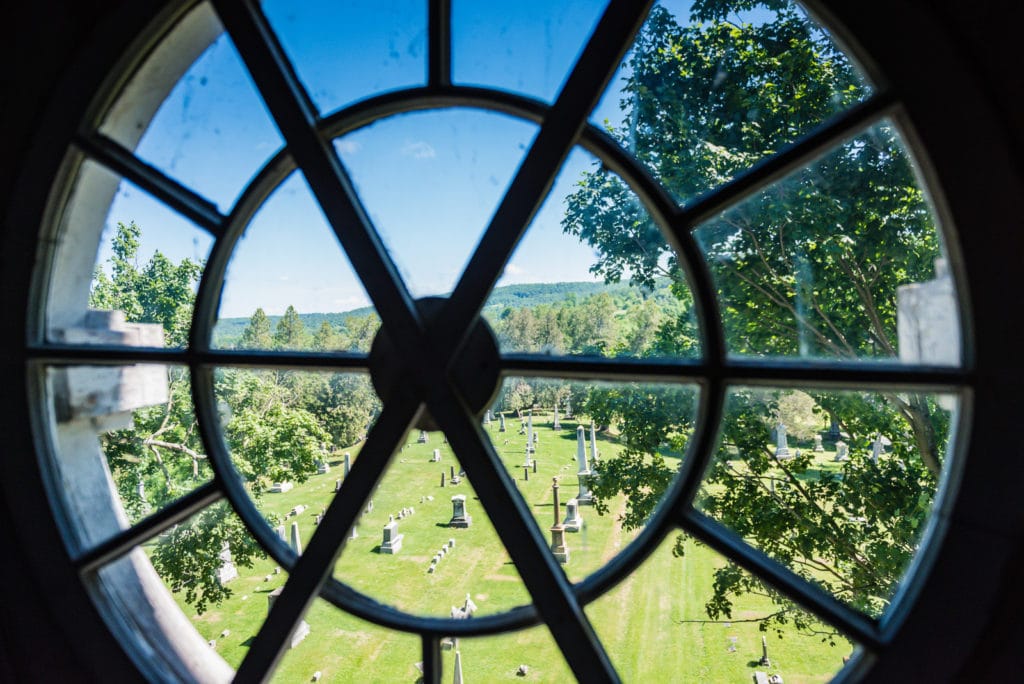 Round window looking out on cemetery on tower at the Old Stone Fort Museum in Schoharie NY.