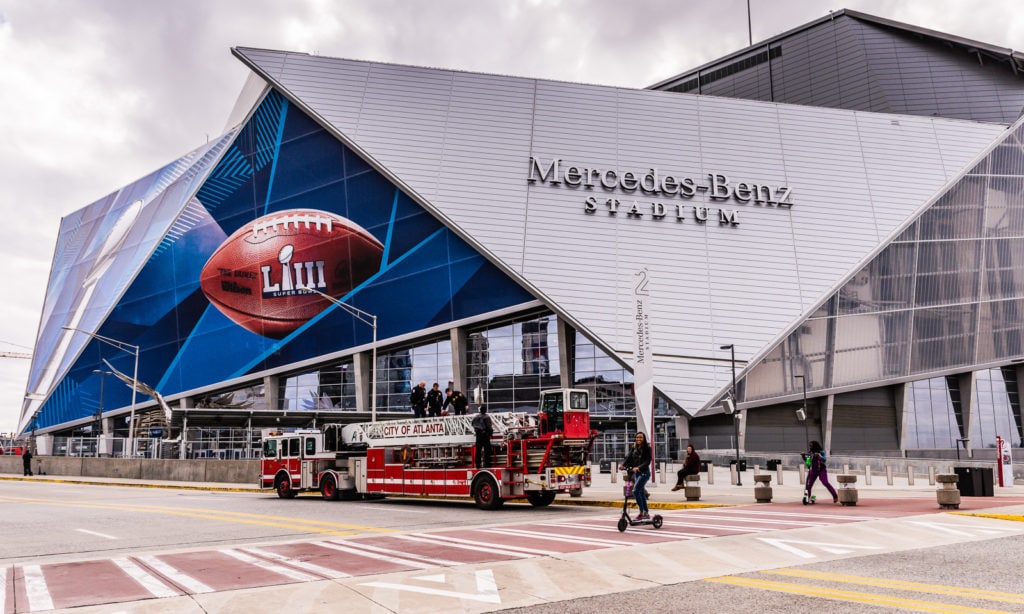 Girl rides scooter in front of Mercedes Benz Stadium in Atlanta GA.