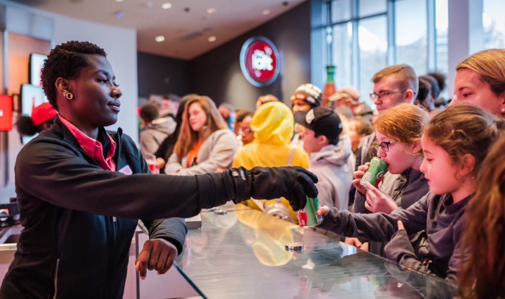 Employee hands out free cans of soda at beginning of World of Coca Cola tour in Atlanta GA.