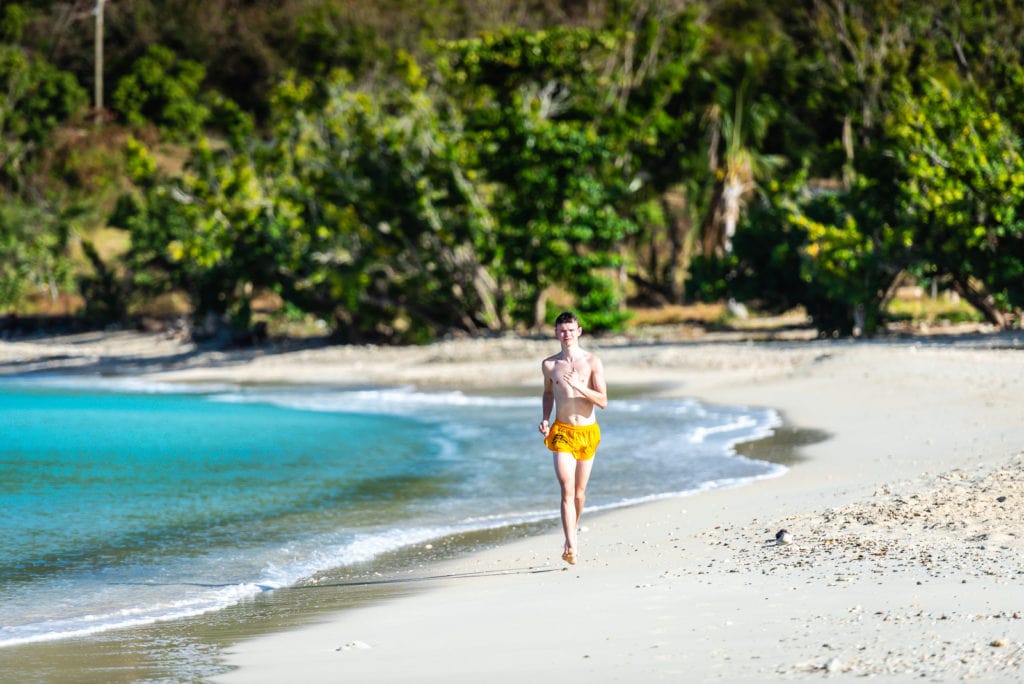 Young man running on shore at Brewers Beach on St. Thomas USVI