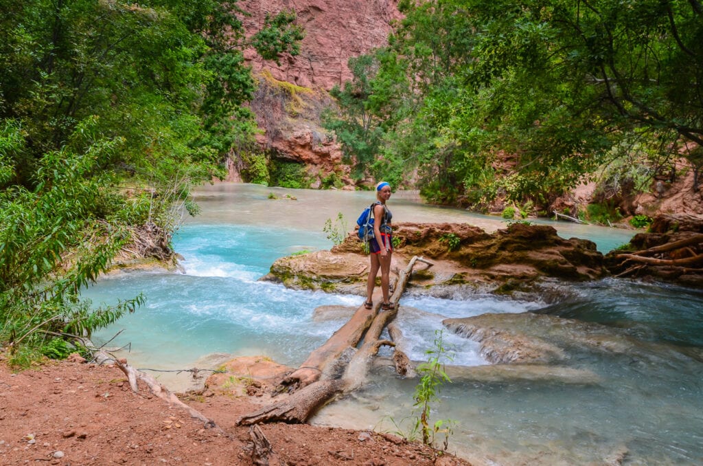 Crossing log bridge on creek bed in Havasu Falls.