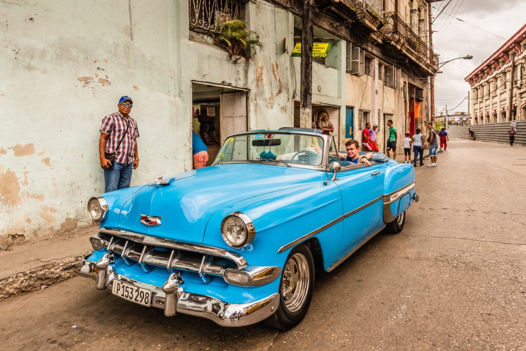 American tourist rides vintage Cuban automobile on tour of Old Havana.