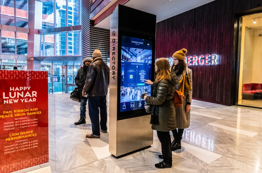 A Hudson Yards Ambassador demonstrates how to order same day tickets at a mall kiosk.