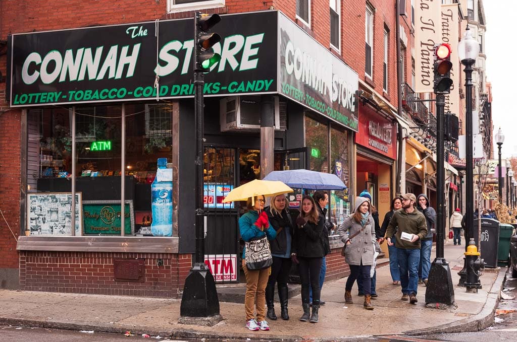 Girls under umbrellas pose in front of The Connah Store in Boston's North End Neighborhood.