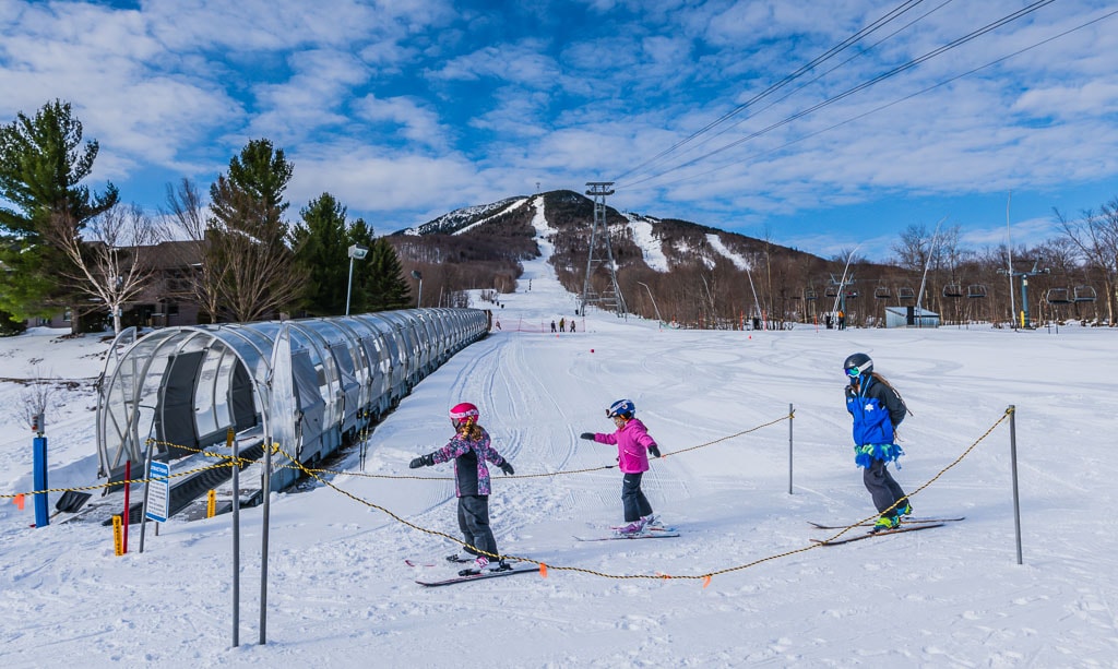 Two kids and instructor at Jay Peak Ski School. They're about to enter the Moving Carpet on a beginner trail.