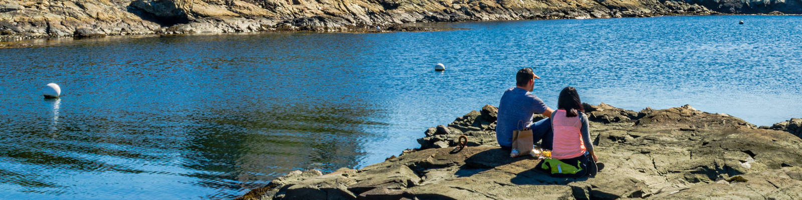 Couple picnic on a rock while on a romantic getaway in Rhode Island.