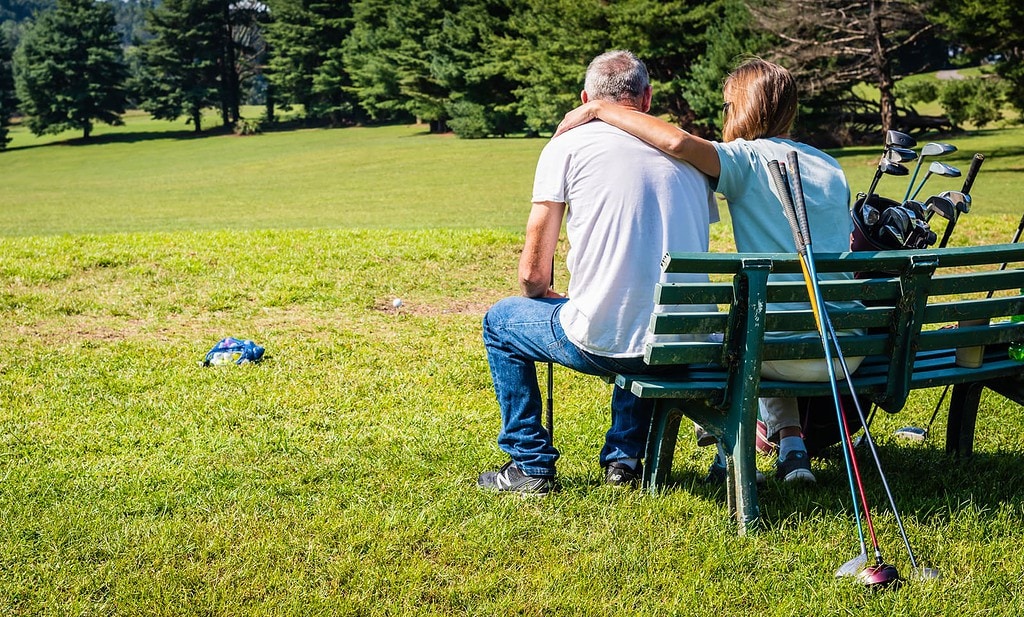 Affectionate couple await turn on golf course at Steele Creek Park