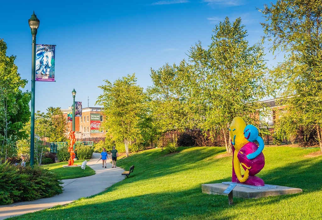 Couple walks in sculpture garden at Founders Park in Johnson City TN.