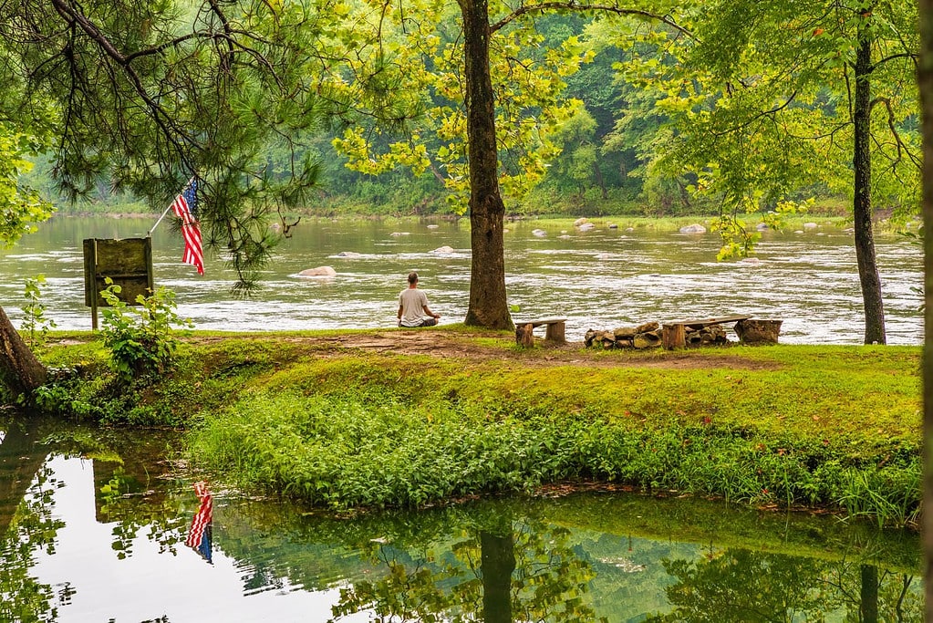 Man meditates on the banks of the Nolichucky River at the USA Raft Adventure Resort.