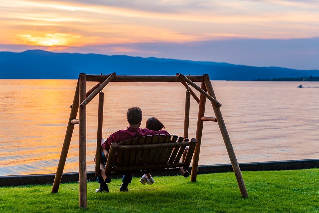 Couple watches Flathead Lake sunset from swing chair.