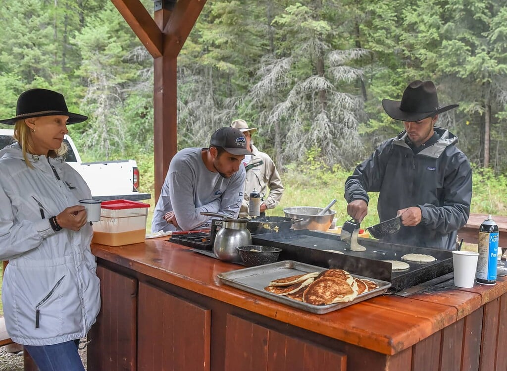 Wranglers cook flapjacks outdoors.