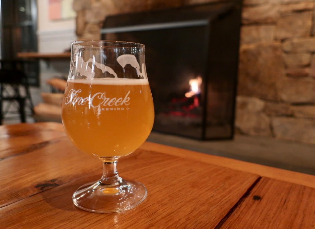 Sour beer from Fine Creek Brewing in front of fireplace