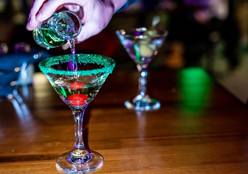 Pouring an appletini into a cocktail glass