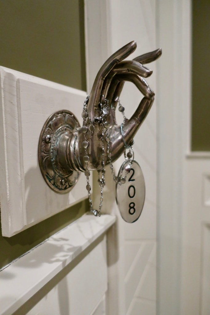 Guest room numbers strung like a necklace around a sculptured hand at Logan Inn