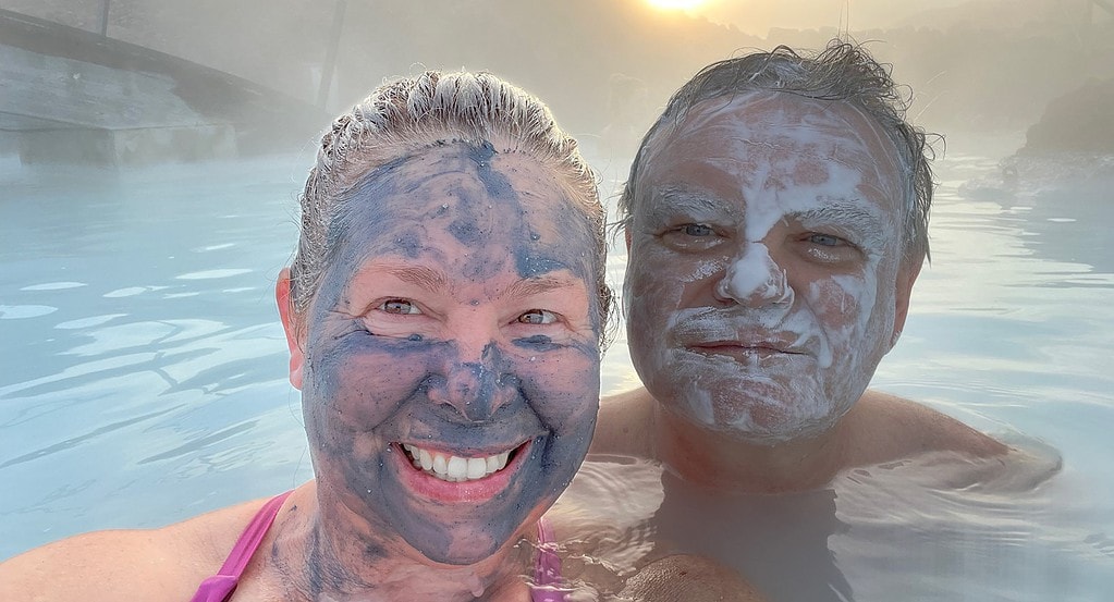 Smiling couple with mud masks on faces at the Blue Lagoon in Iceland.
