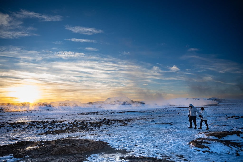 Couple walks on snow at Hverir.