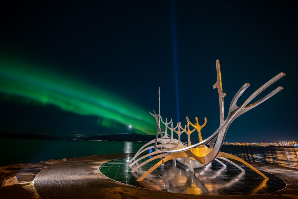 Northern Lights and the Imagine Peace Tower Lights in front of the Sun Voyager.