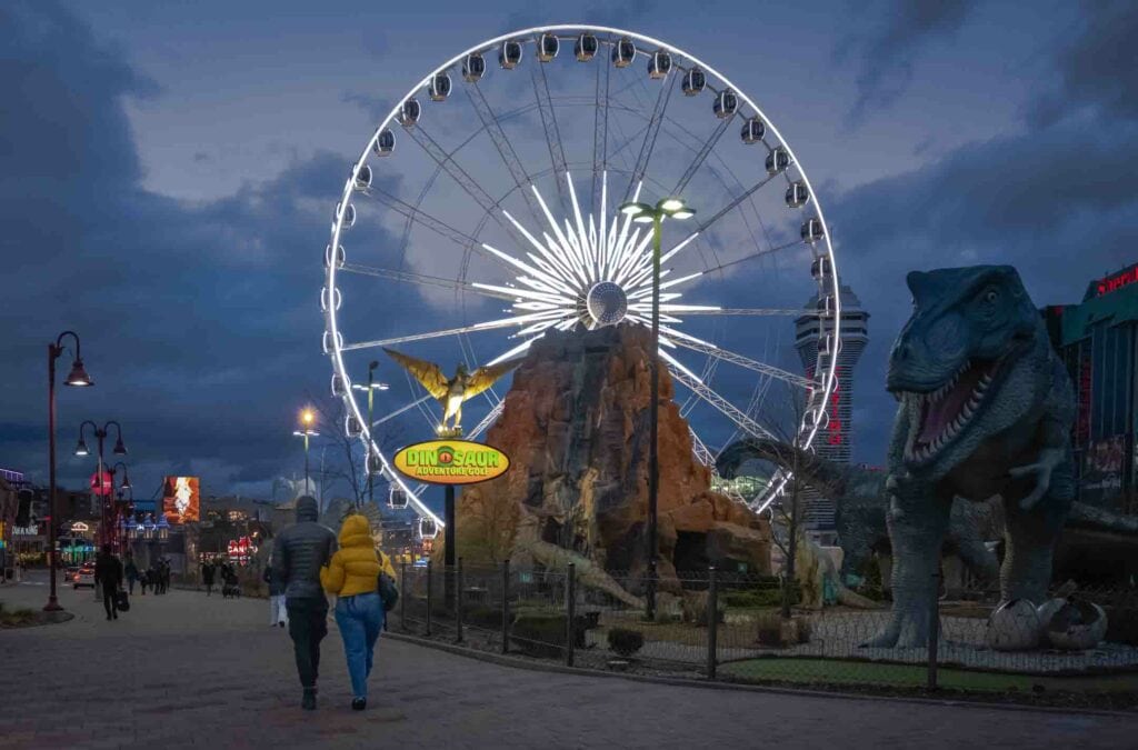 Couple walking into Clifton Hills with Dinosaur mini golf and Niagara SkyWheel