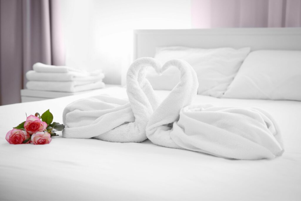 Swan shaped towels and roses add a romantic flourish to a hotel room.