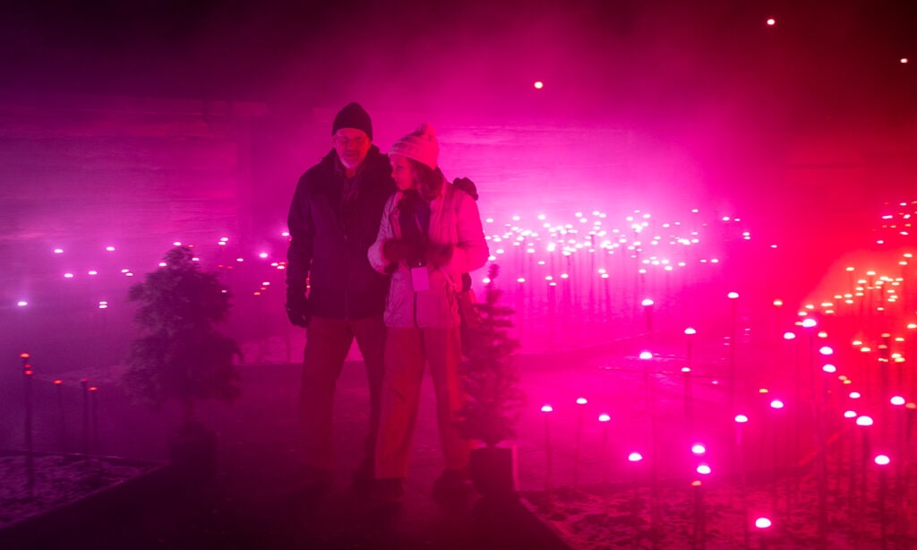 Couple strolls through atmospheric lights at Lake George Winter's Dream