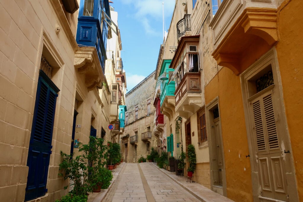 Malta street with colorful 2nd floor exterior enclosed balconies.