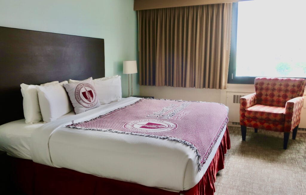 Hotel UMass guest room with University of Massachusetts woven throw on bed